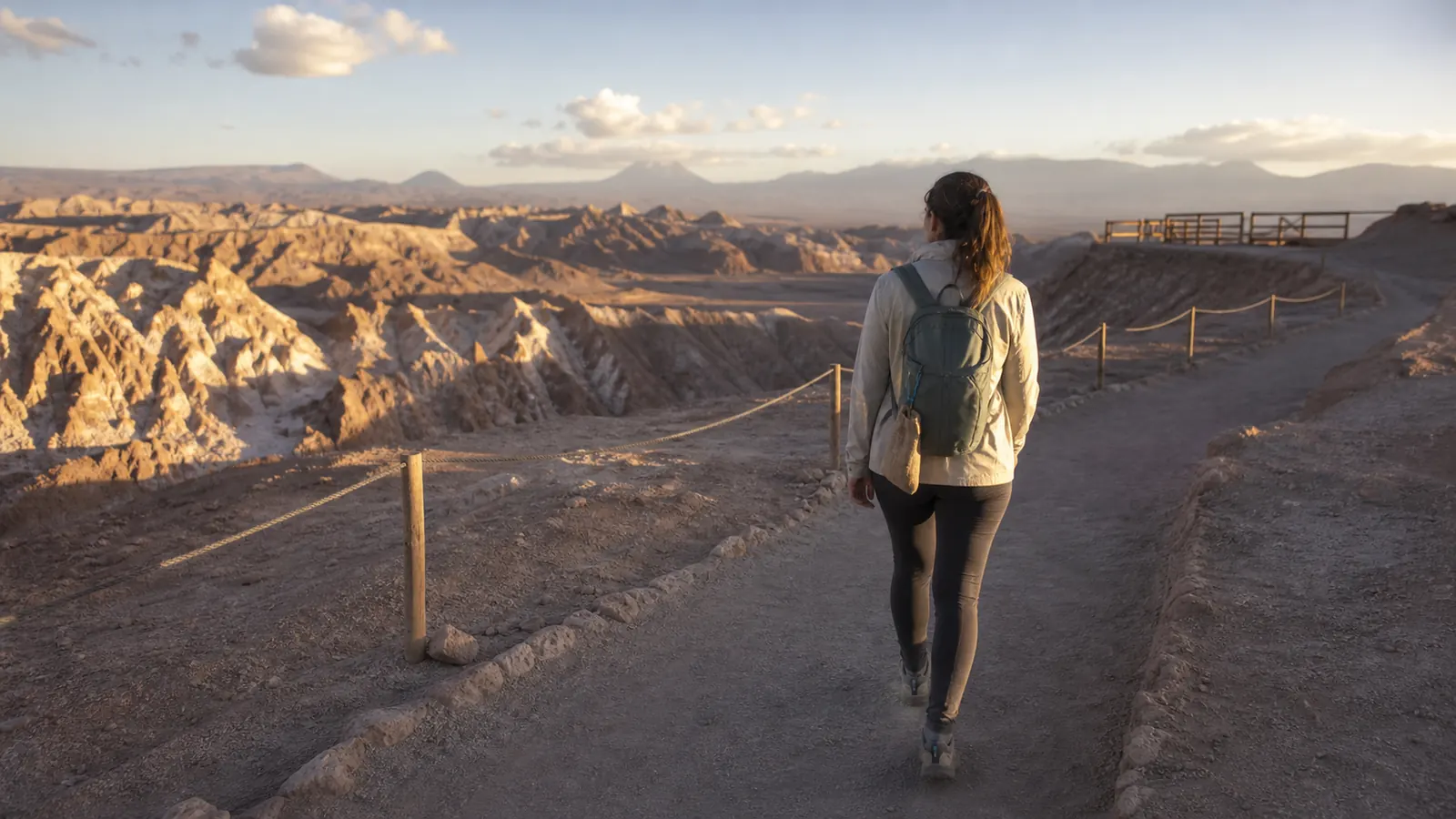 Traveler staying on a marked Valle de la Luna path with a reusable pouch and small backpack